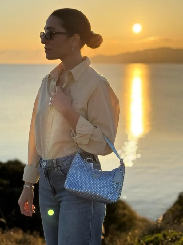foto con mare all'orizzonte e ragazza con in braccio una borsa di lusso di seconda mano
